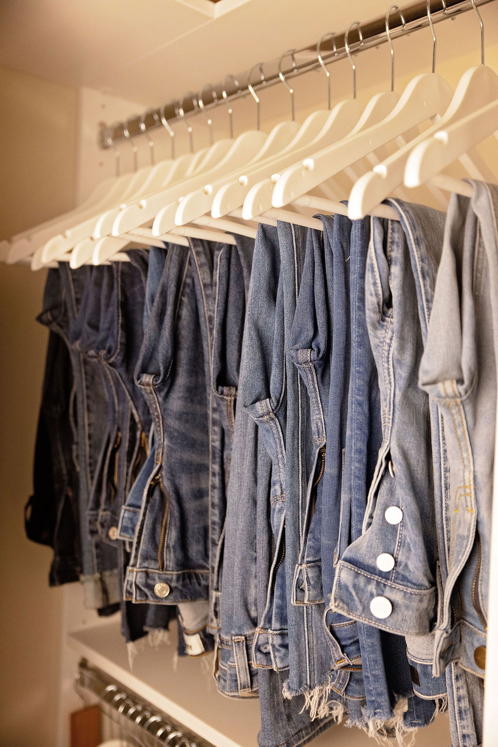 Row of denim jackets on hangers in a closet